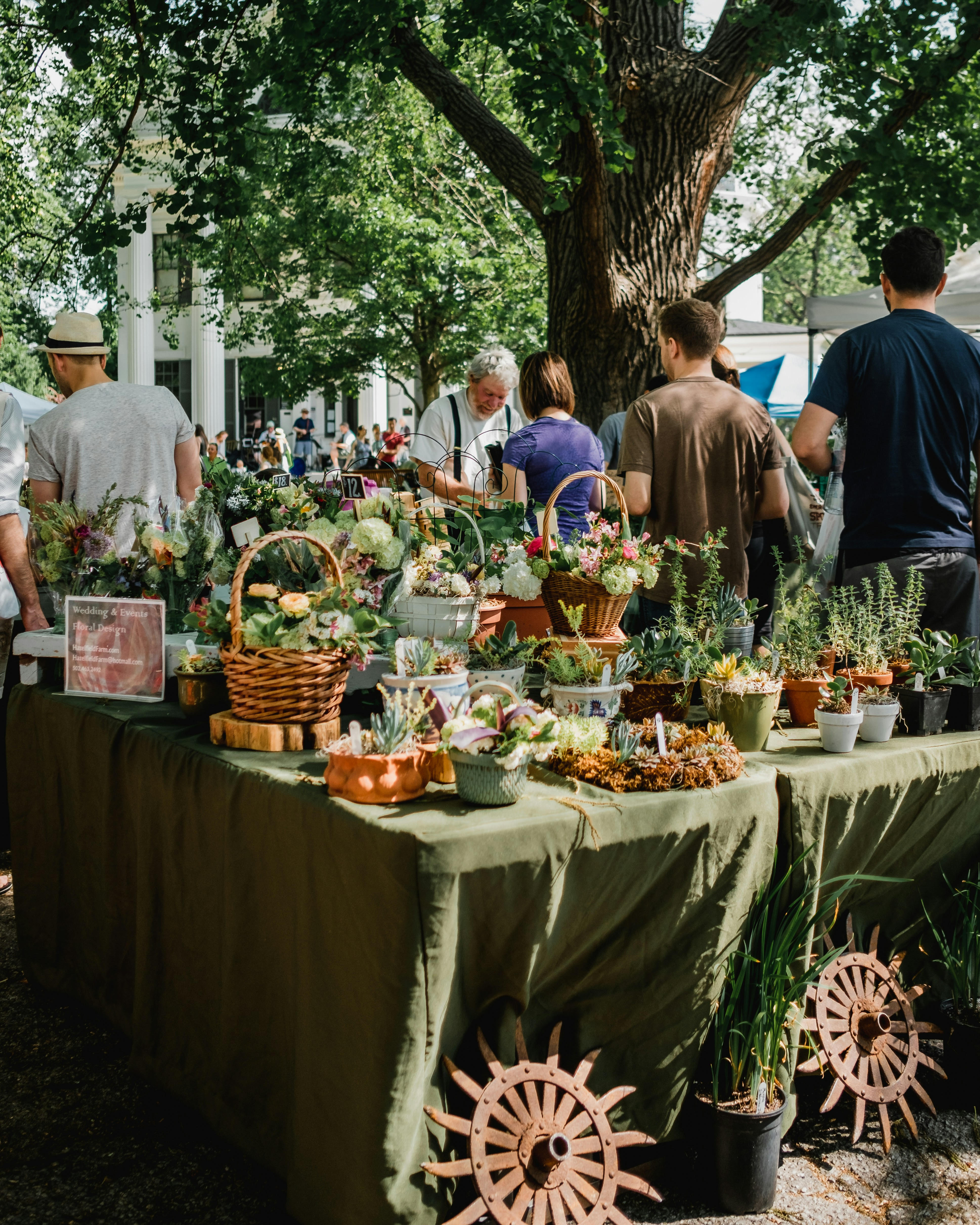 Farmers Market with several people talking. It appears a young woman is making a purchase from the salesman.